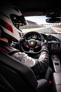 Un pilote installé au volant d'une voiture sportive sur un circuit automobile. L'image représente l'expérience immersive d'un stage de pilotage
